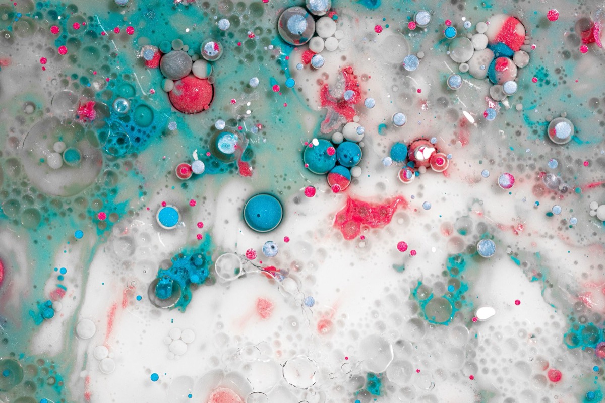 Close-up of a painted surface showing multiple small to medium-sized bubbles and blisters forming on the paint film.