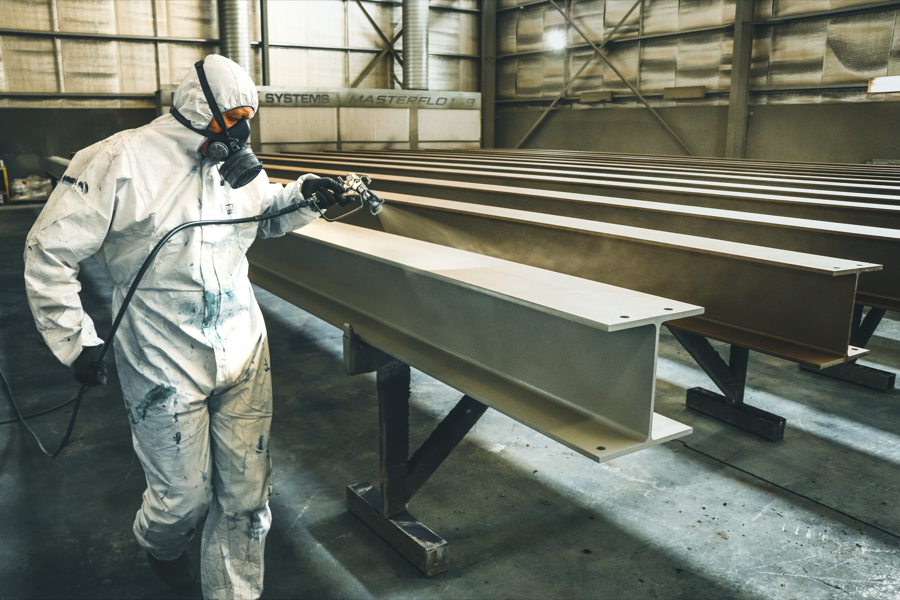 A technician carefully applying primer to a repaired car panel area.