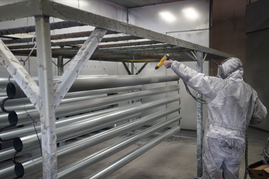 Person applying automotive primer to a sanded car panel, preparing it for new paint.